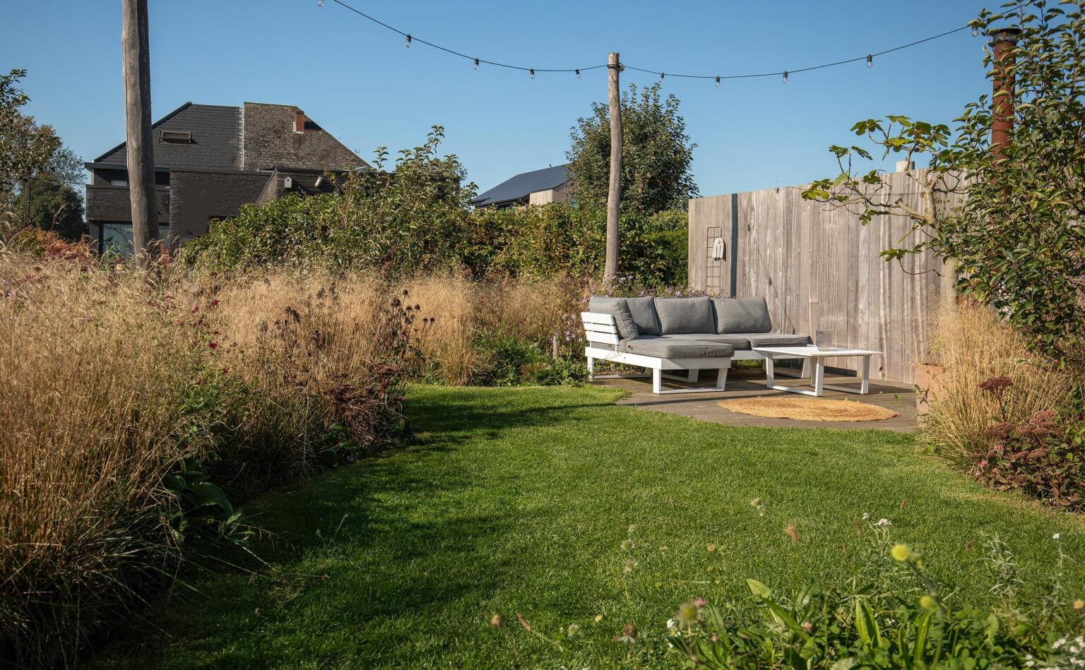 Greenarchitects stefaan willems landschapsarchitect serskamp moderne woning kleiklinkers terras padoek tuinmuur houten palen bloeirijk grasland sfeerlampen loungeset 01